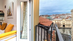A balcony with a city view, a bed with yellow pillows, and a door with a geometric pattern. - ☀️❤️Historic penthouse in the heart of Santander ! ❤️☀️ (Santander)