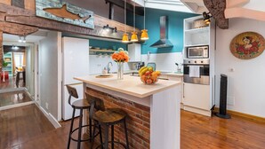 A kitchen with a central island, wooden bar stools, a hanging light fixture, and a decorative wall piece. - ☀️❤️Historic penthouse in the heart of Santander ! ❤️☀️ (Santander)