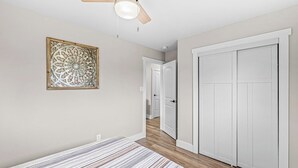 A bedroom with a bed, a ceiling fan, a decorative wall piece, and a wardrobe. - Renovated Urban Oasis in Indy (Indianapolis)