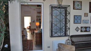 A living room with a large window, a sofa, a bench, and a decorative wall with tiles. - Volta House (Palermo)