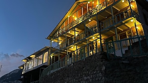 A multi-story building with balconies, wooden railings, and a stone retaining wall.