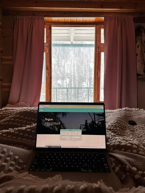 A laptop on a bed with a window view. - Firgun Chapter Sajwaad (Banjar)