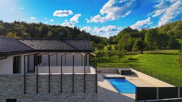 Set amidst lush greenery and hills, this property offers a serene environment with a swimming pool and well-maintained lawn.
