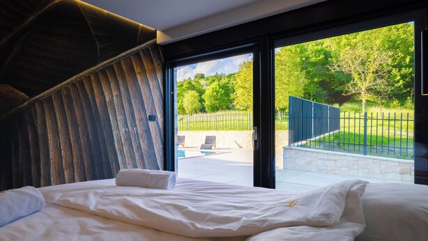 Une chambre dotée d’un grand lit, donnant sur un jardin, et présentant un design moderne.