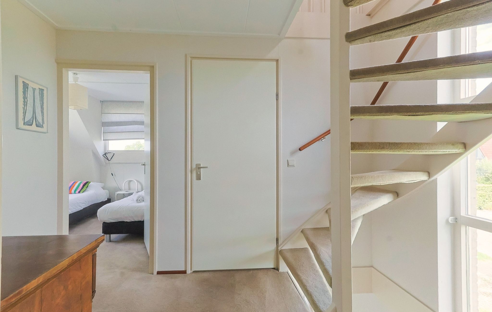 A hotel room with a bed, bedside table, and a window.