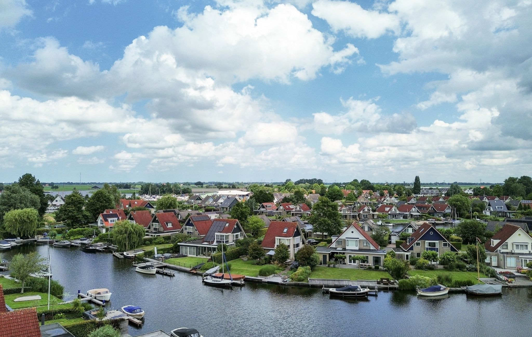 A residential area with houses, a canal, and boats.