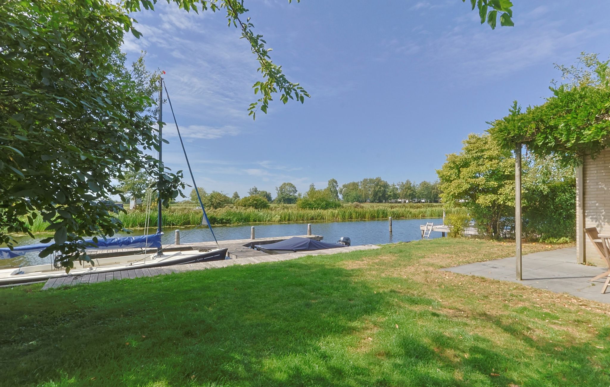 Une propriété au bord du lac, dotée d’une pelouse verdoyante, d’un quai et de bateaux.