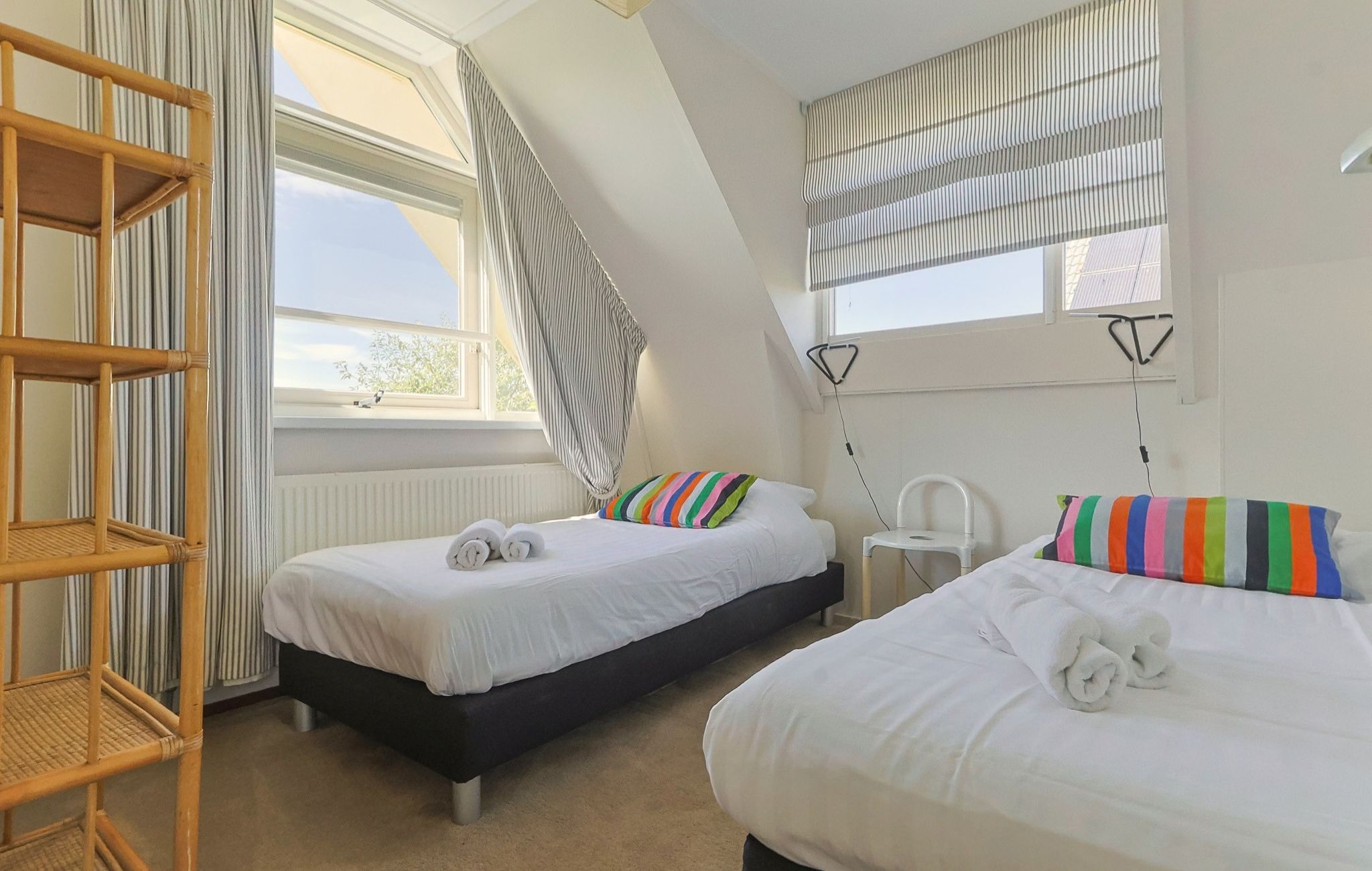 A room with two beds, a window, a radiator, and a chair.