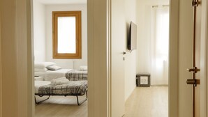 A hotel room with two beds, a wooden-framed window, a television, and a trash bin. - The Glass House (The Art of Murano) Apartment in the heart of Venice (Venezia)