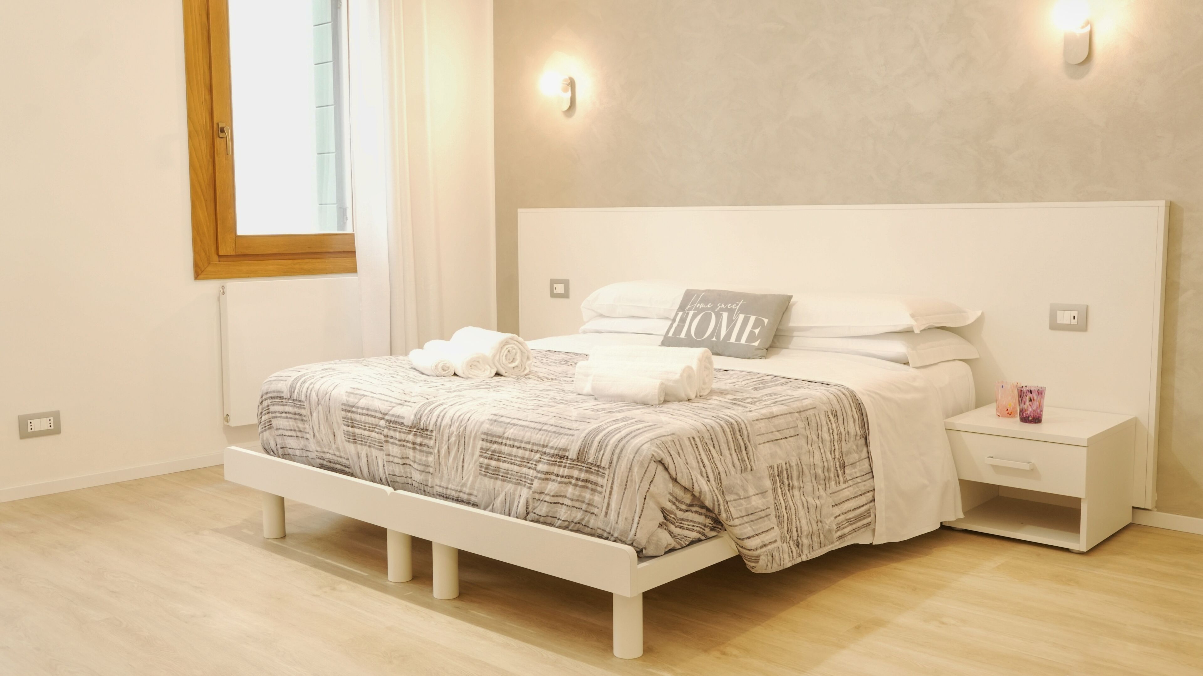 A bedroom with a bed, bedside tables, and a window.
