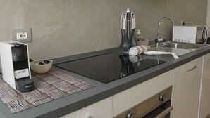 A modern kitchen with a black countertop, a built-in stove, a sink, and a coffee machine. - The Glass House (The Art of Murano) Apartment in the heart of Venice (Venezia)