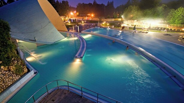 A large outdoor swimming pool with a unique architectural feature resembling a large white shell. - Harmony of romance and nature for two, in a double bedroom (Miskolc)