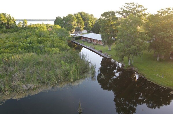 Un chalet situé au bord de la rivière, doté d’un quai, entouré d’une végétation luxuriante et bordant un lac paisible.