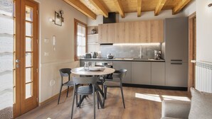 Een moderne keuken met houten kastjes, een ronde eettafel met stoelen en een inbouwoven.