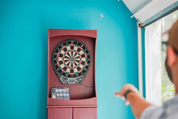 A dartboard mounted on a teal wall with a dartboard case below it.