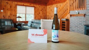 Interior de madera con una mesa mostrando una botella de vino y una tarjeta de bienvenida.