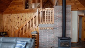 Una sala de estar acogedora con una escalera de madera, una chimenea y un sofá de cuero.