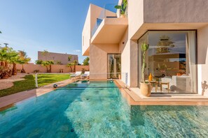 A modern house with a swimming pool, a balcony, and a view of the surrounding landscape.