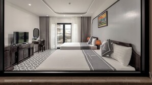 Una camera d'albergo con un letto grande, una TV, una scrivania e un balcone con tende.