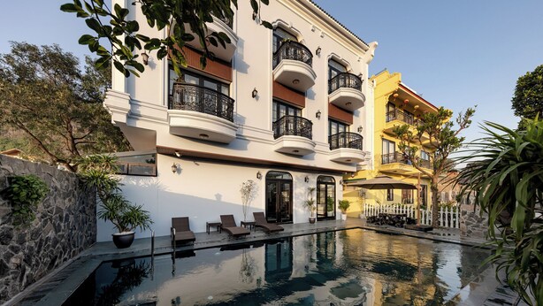 Un hotel con piscina, diversi balconi e zone relax all'aperto.