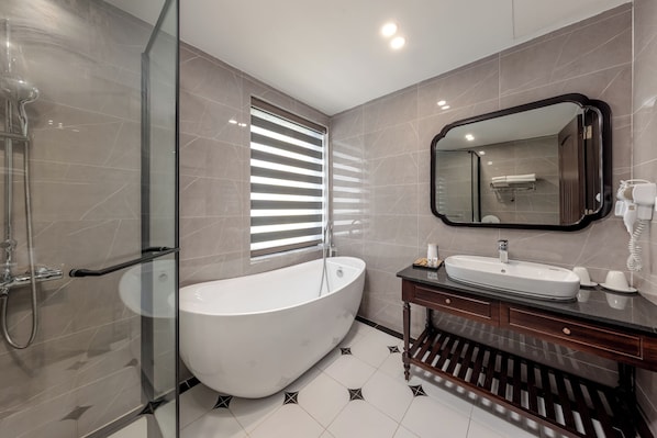 A modern bathroom with a freestanding bathtub, a glass-enclosed shower, a vanity with a mirror, and a towel rack.