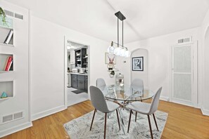 A modern dining area with a glass table, grey chairs, and a black pendant light.