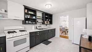 Una cocina moderna con armarios blancos y gris oscuro, una estufa blanca y una encimera negra.