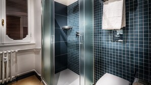 A modern bathroom with a glass shower enclosure, a white toilet, and a towel rack. - Trinità Grand Suite (Rome)