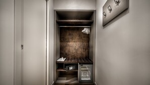 A compact walk-in closet with a built-in refrigerator, shelves, and hanging storage. - Trinità Grand Suite (Rome)