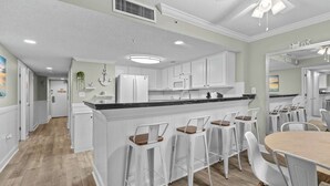 A modern kitchen with white cabinetry, a black countertop, and a central island with bar stools.