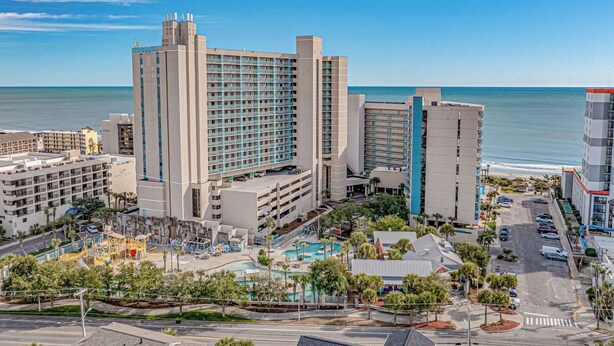 A hotel with multiple floors, a swimming pool, and a view of the ocean.