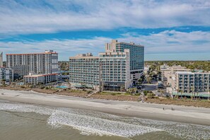 A coastal hotel complex with multiple high-rise buildings, a beachfront, and a parking area.