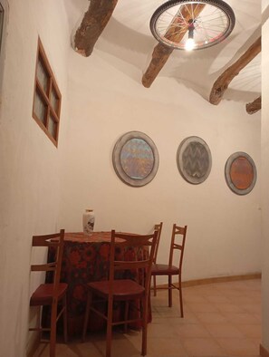 A dining area with a round table and chairs, a window, and three decorative plates on the wall. - Casa Lola          . (Busquístar)