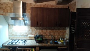 Eine Küche mit Gasherd, Spüle und Holzschränken.