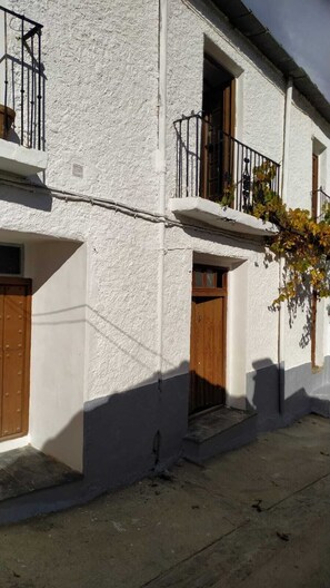 A two-story building with white walls and wooden doors. - Casa Lola          . (Busquístar)