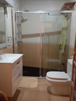 A bathroom with a glass-enclosed shower, a sink, and a toilet.