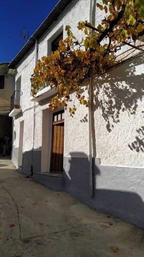 Ein weißes Gebäude mit Holztür und einem kleinen Balkon.