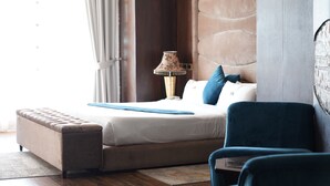 Une chambre à coucher avec un lit, un banc, une lampe et une chaise.