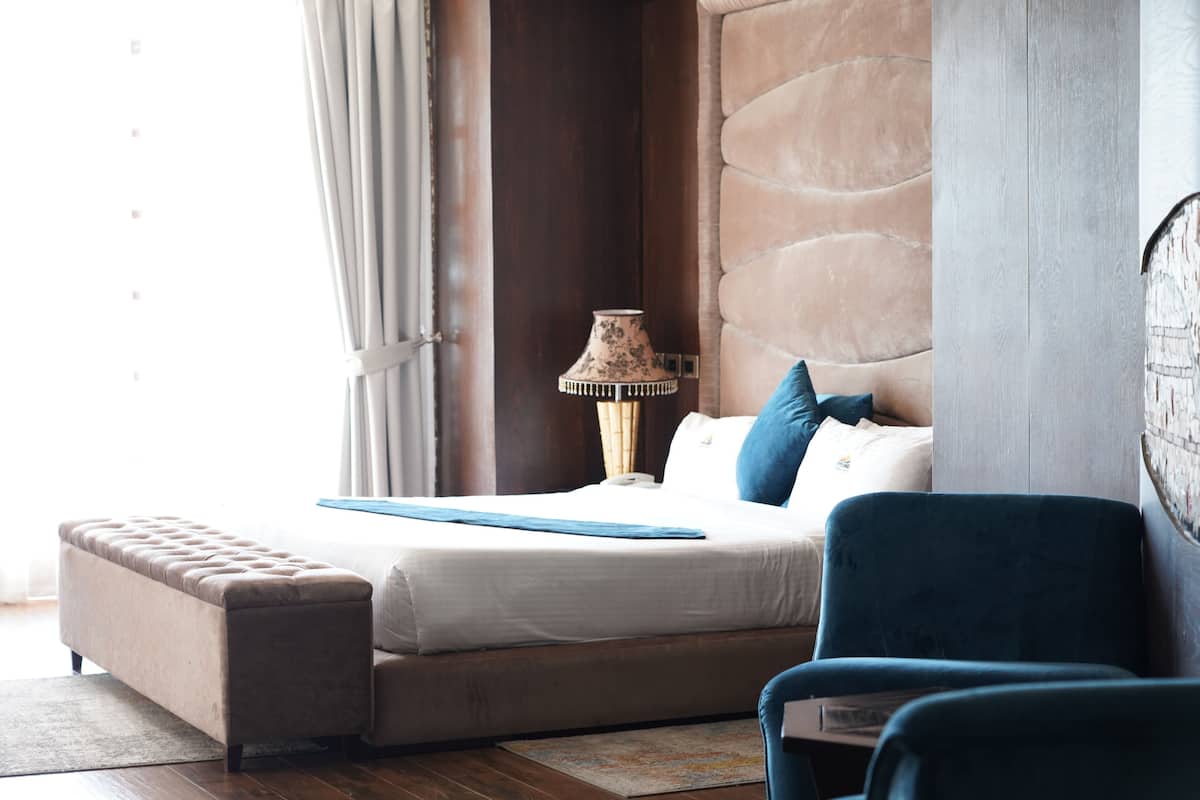 Un dormitorio con una cama, un banco, una lámpara y una silla.