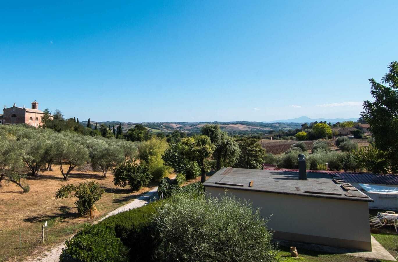 Une villa offrant une vue sur des collines verdoyantes et une chaîne de montagnes lointaine.