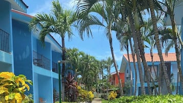 A resort with a swimming pool surrounded by lush greenery and palm trees.