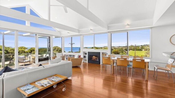 Amplia sala de estar con chimenea, ventanas grandes y comedor.
