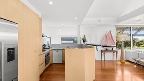Una cocina moderna con una isla central, electrodomésticos de acero inoxidable y vistas al exterior.