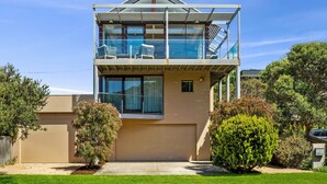Una casa moderna de dos pisos con balcón, una ventana pequeña y un césped bien cuidado.