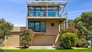 Una moderna casa a due piani con un balcone, una piccola finestra e un prato curato.