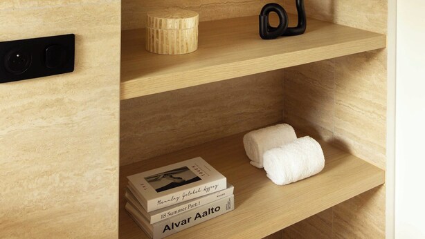 Ein Holzregal mit Dekorationen und einer Wandleuchte.