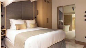 Ein modernes Schlafzimmer mit einem großen Bett, einem Holzschrank und einem durch eine offene Tür einsehbaren Badezimmer.
