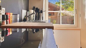 Eine moderne Küche mit großem Fenster, Holz Arbeitsplatte und diversen Küchenutensilien.