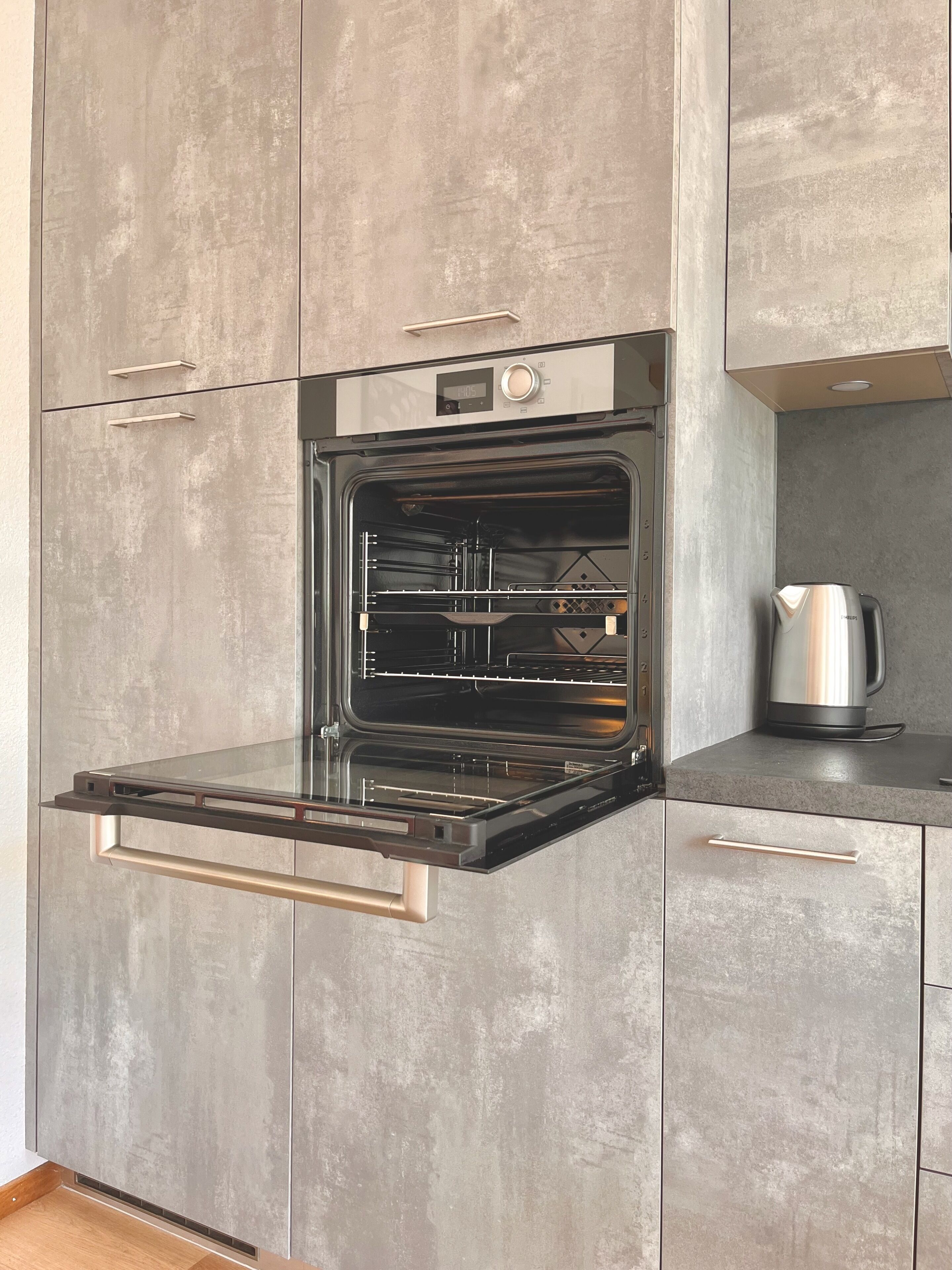 Een moderne keuken met een inbouwoven, een koffiezetapparaat en een strak aanrecht.