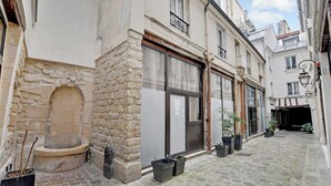 A narrow cobblestone street with buildings on either side, stone walls, and potted plants. - Elegant Apartment -2br-4p- Le Marais (Paris)